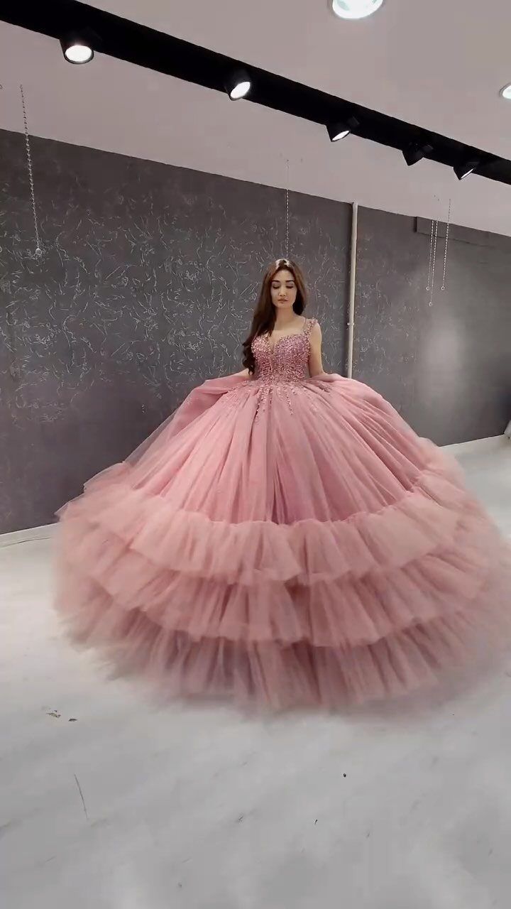 Woman in a giant pink ruffled ballgown standing in a grey studio