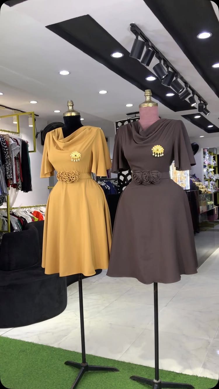 Two cowl neck dresses in mustard yellow and brown on store mannequins.