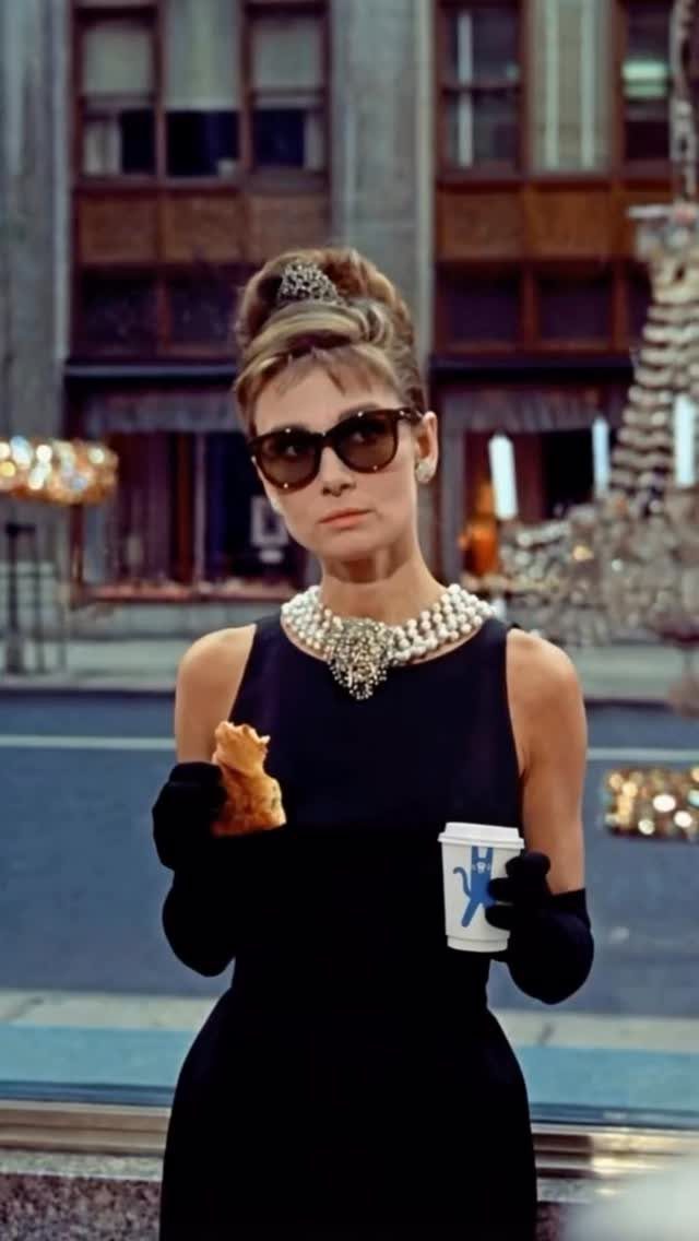 Woman in a classic black dress, pearls, and sunglasses on a city street