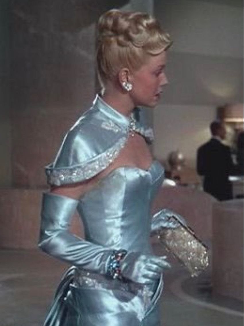 Woman in a shimmering light blue satin gown and opera gloves in profile
