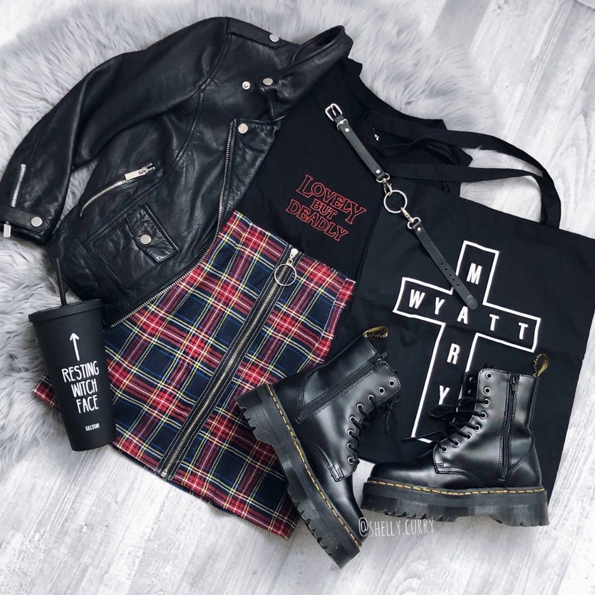 Gothic outfit flat lay with leather jacket, plaid skirt, and black combat boots.