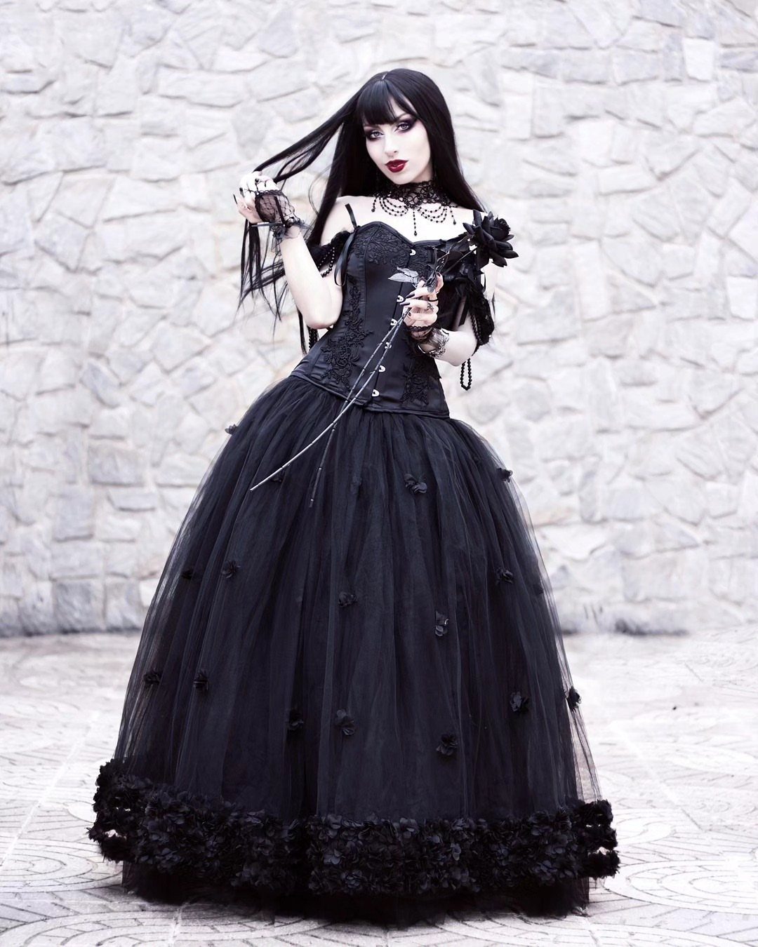 Woman in a voluminous black gothic gown with corset and tulle skirt.