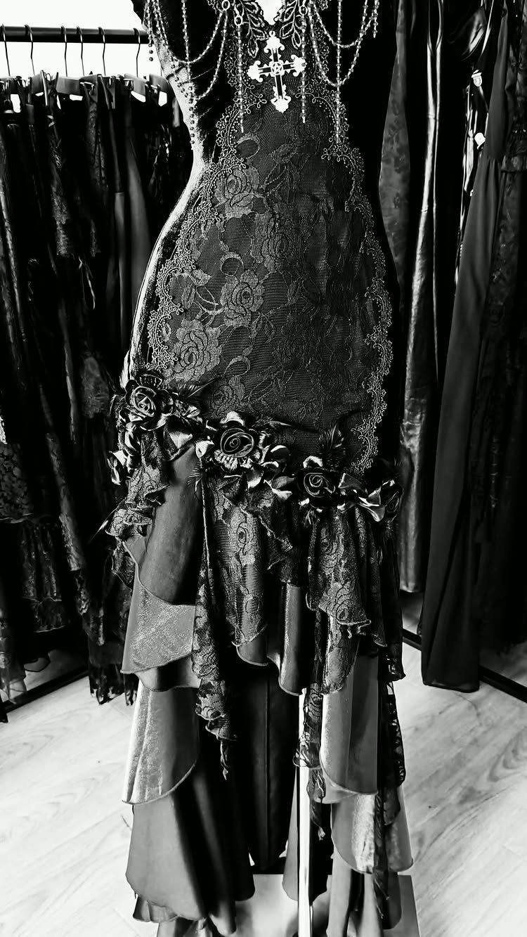 Floor-length black gothic dress with lace, ruffles, and silver cross chain jewelry.