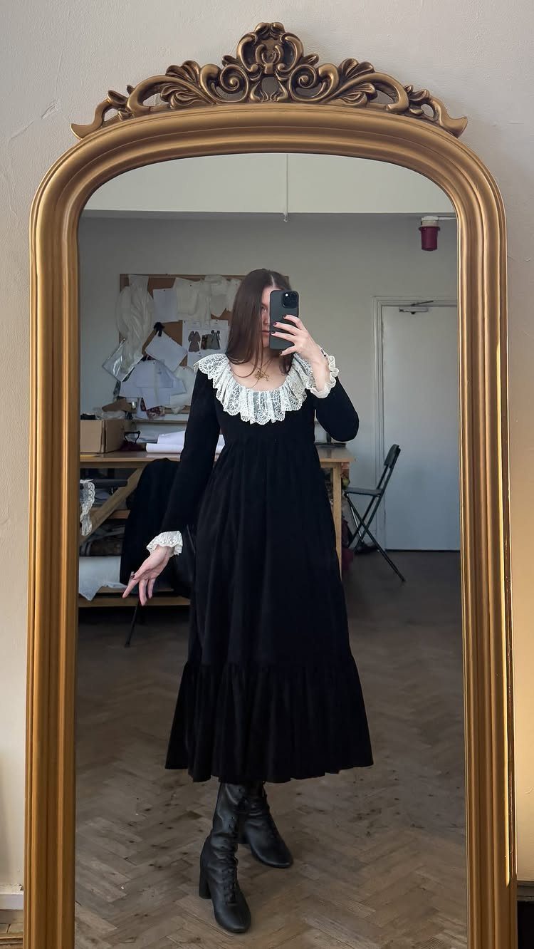 Person in a black velvet dress with white lace collar and cuffs.
