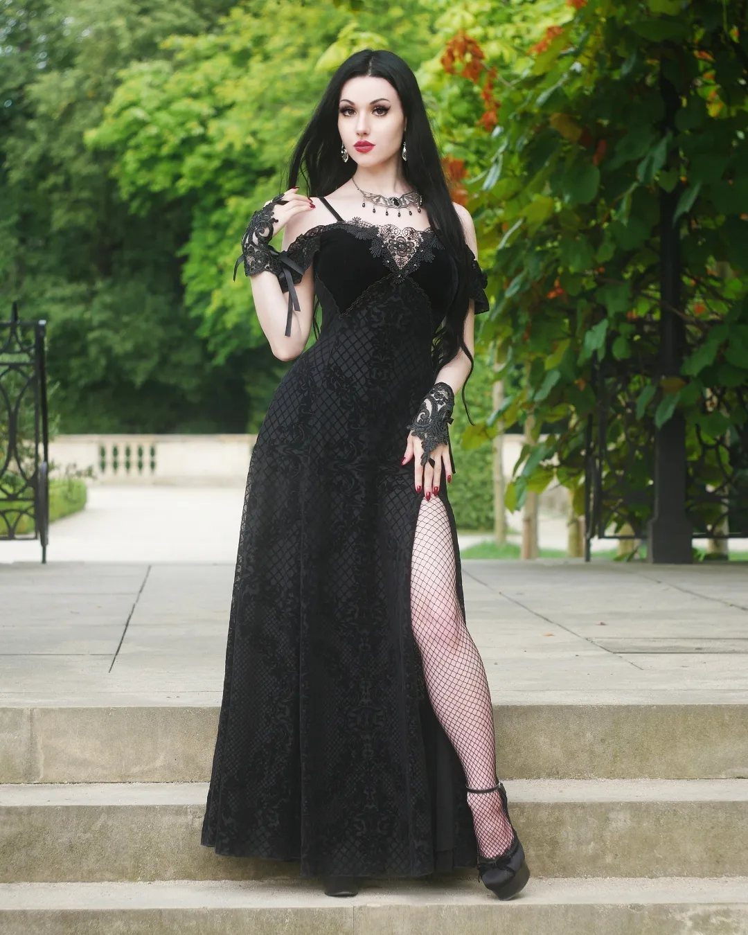 Woman in a long black vintage lace romantic dress standing on stone steps.