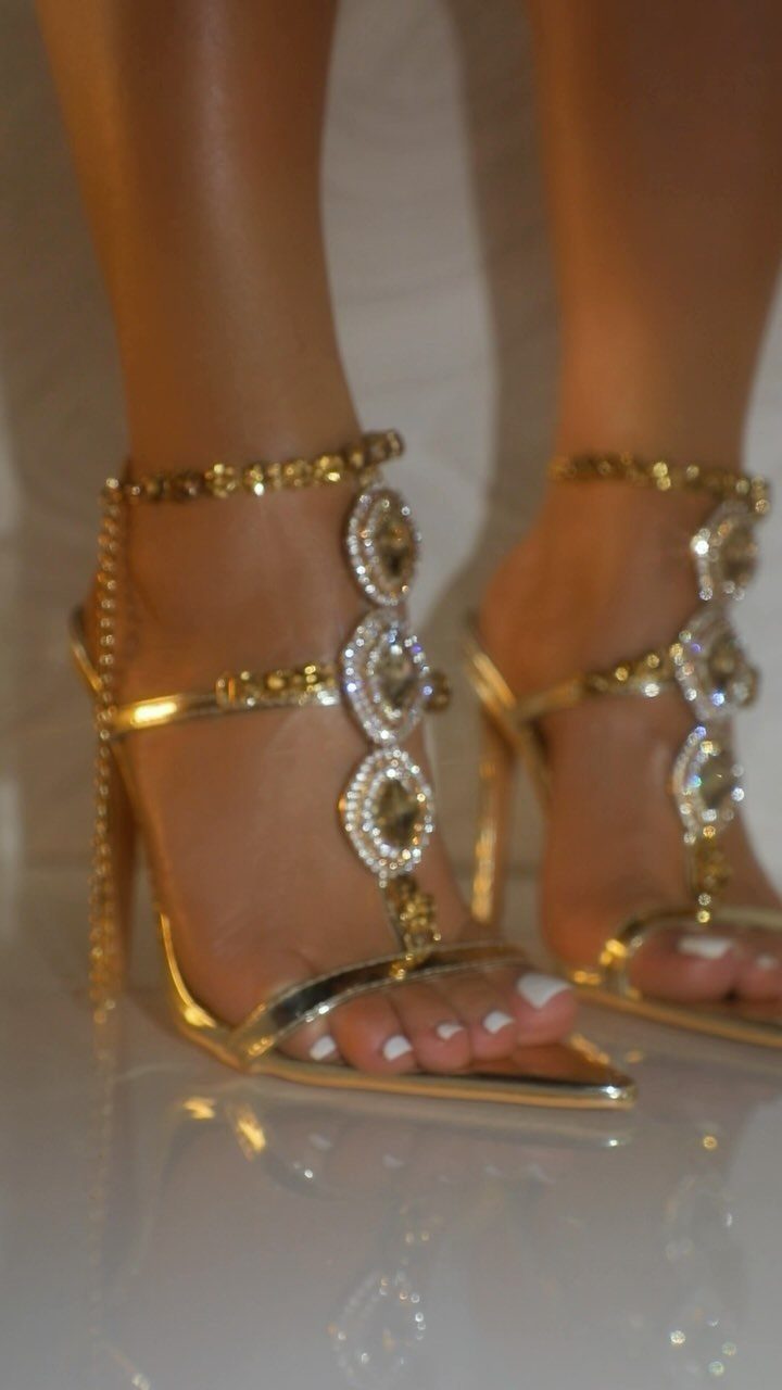Gold strappy high-heeled sandals embellished with sparkling diamond-like charms and gold beads.