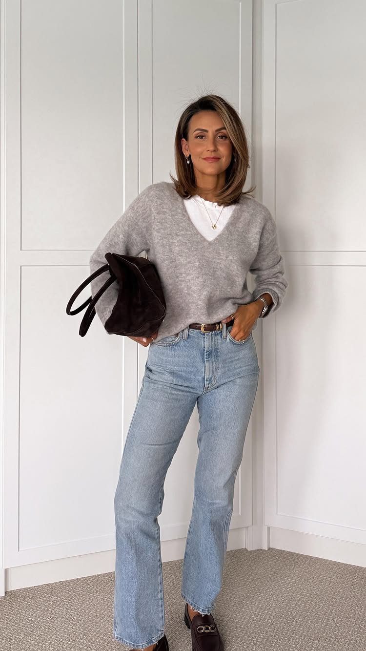 Woman wearing a grey V-neck sweater and light blue high-waisted baggy jeans.