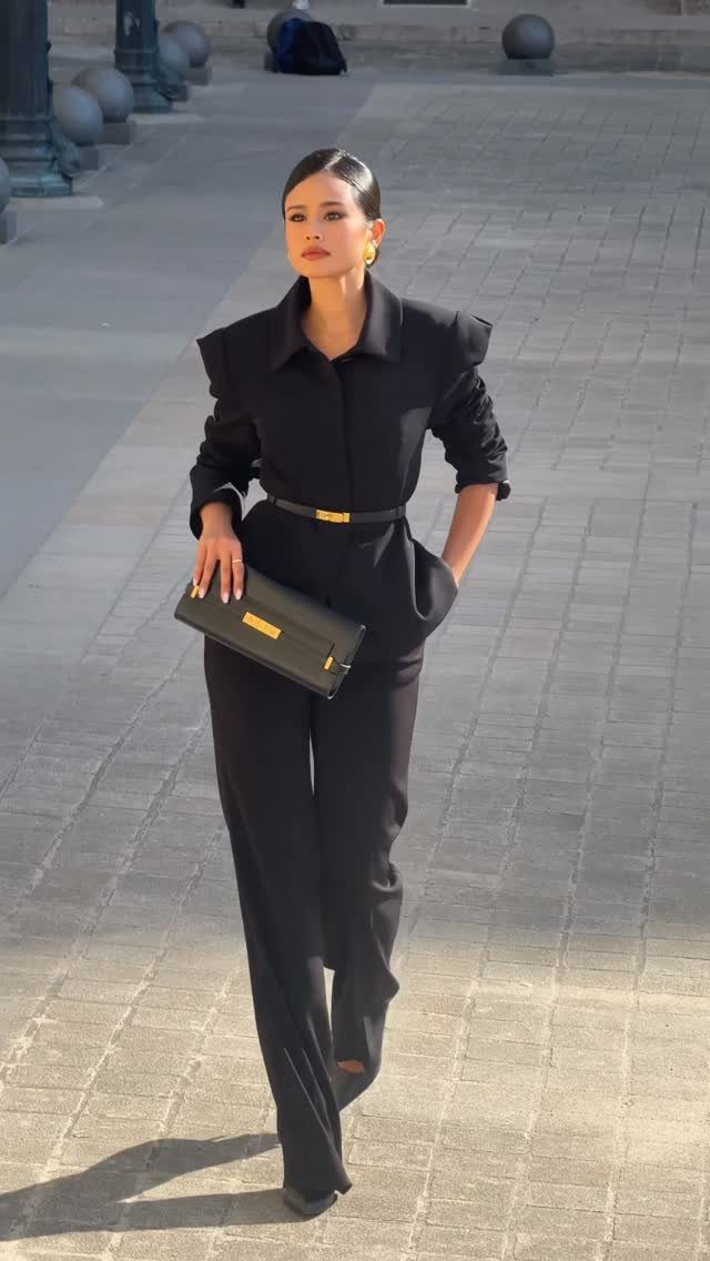 Woman in a black oversized blazer with large shoulder pads and matching trousers.