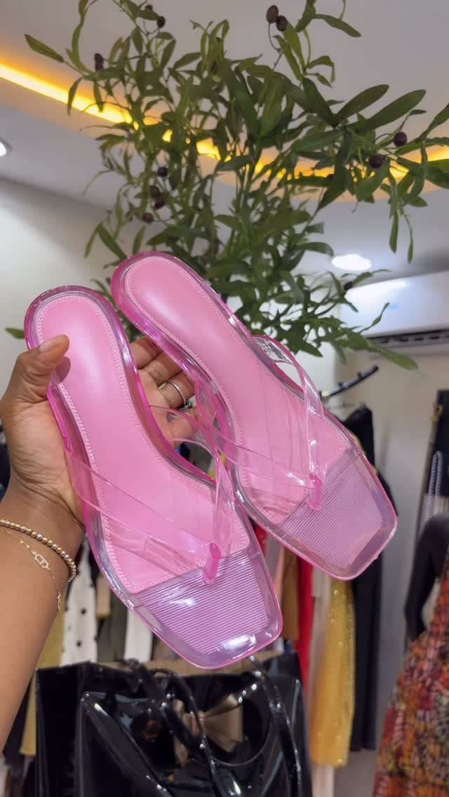 Pink jelly thong kitten heels with square toes held by a hand.