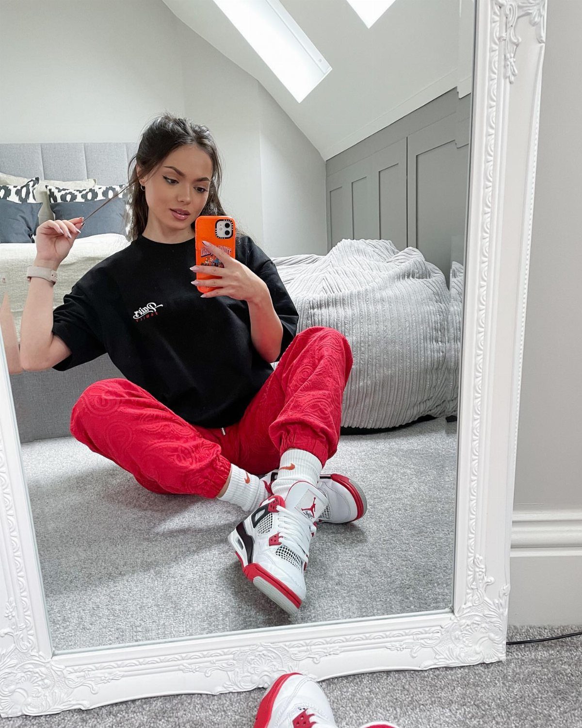 Woman in red joggers and red and white Air Jordan retro sneakers taking selfie