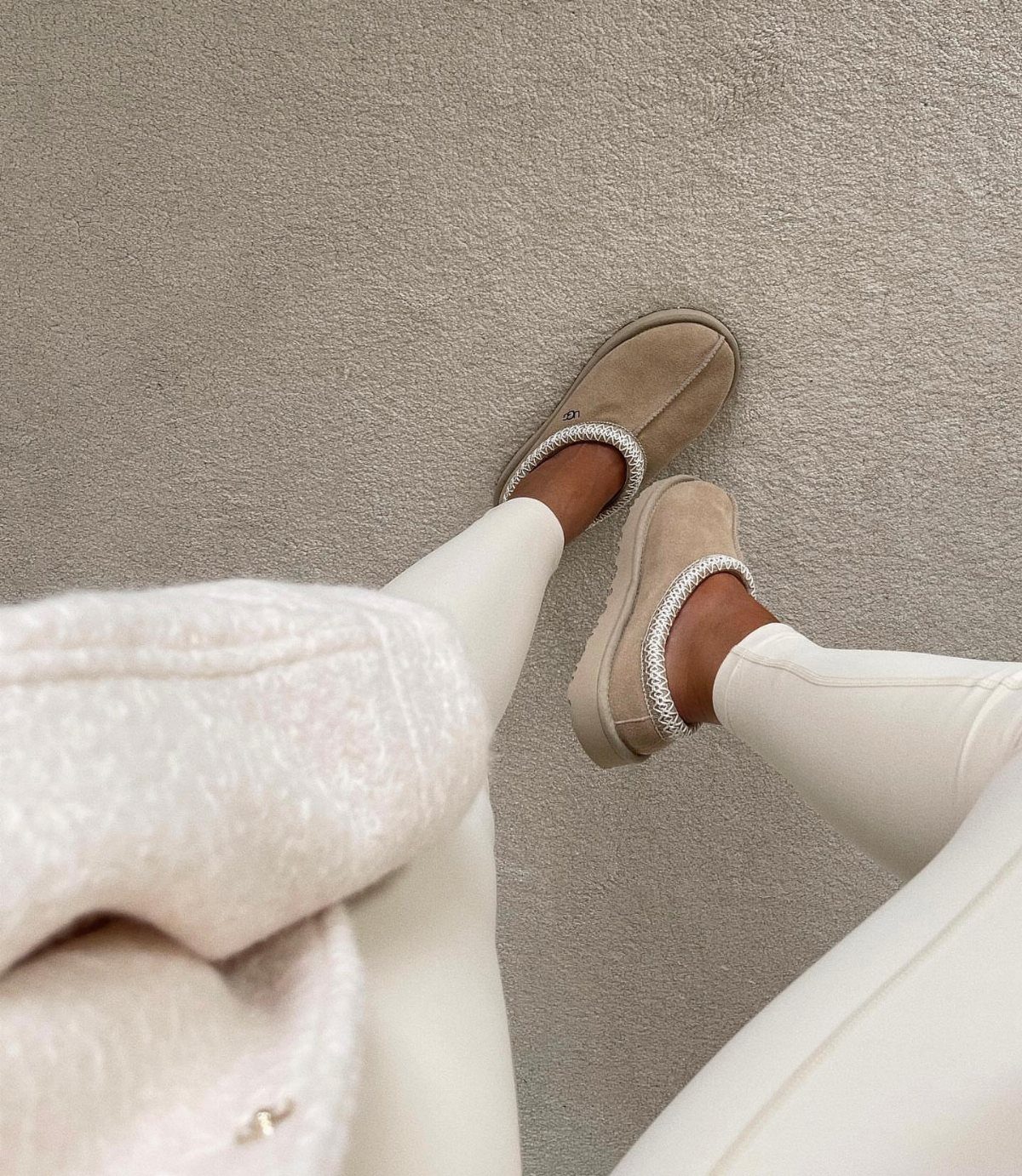 Leggings and Ugg Boots: 6 Outfit Ideas for Cold Days 4 Cream leggings and beige Ugg boots with glitter trim on a beige carpet.