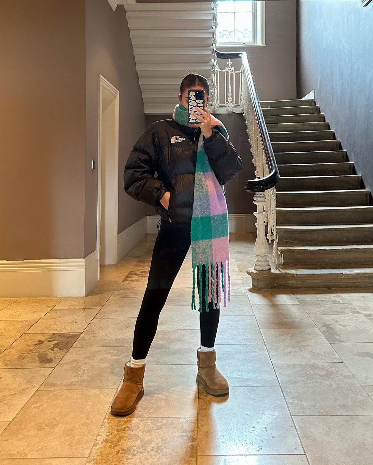 Leggings and Ugg Boots: 6 Outfit Ideas for Cold Days 3 Person wearing a black puffy jacket, black leggings, and tan Ugg boots.
