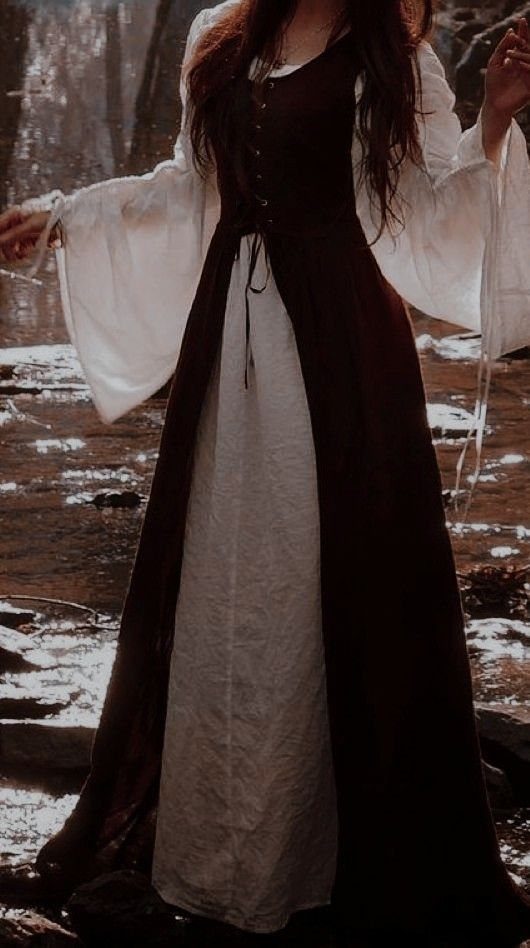 Person in a brown medieval bodice dress and white blouse in a forest