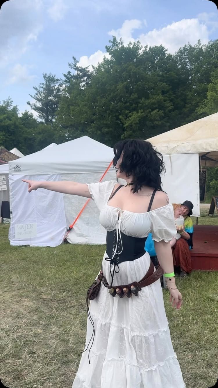 Woman in white blouse and tiered skirt with black corset at outdoor fair