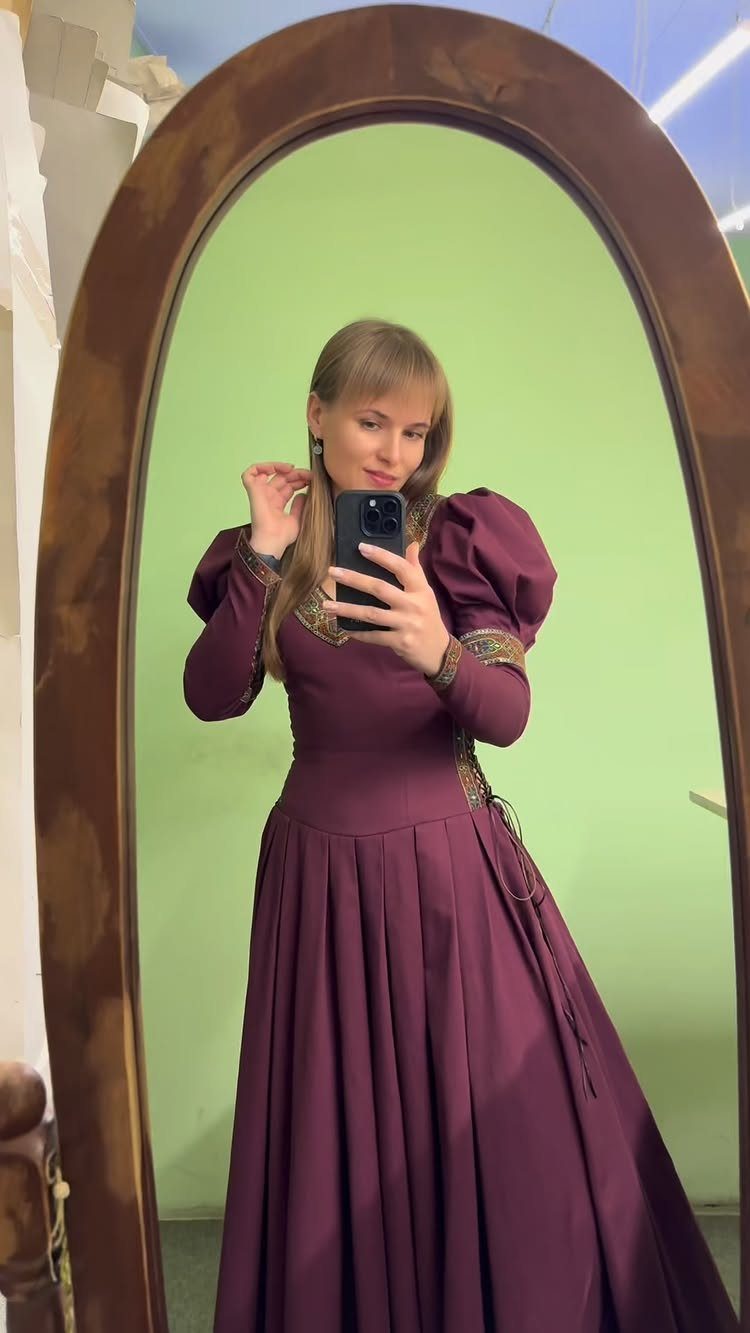 Woman in a purple medieval dress with puffed sleeves posing in a mirror