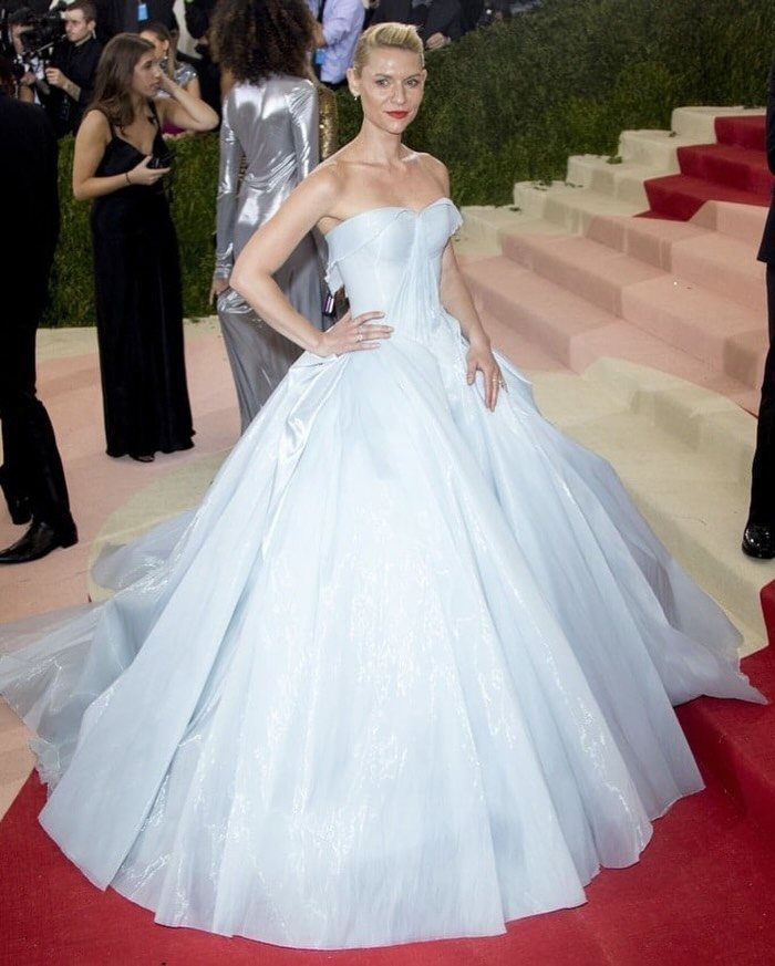 Woman in a voluminous light blue strapless ballgown posing on a red carpet.