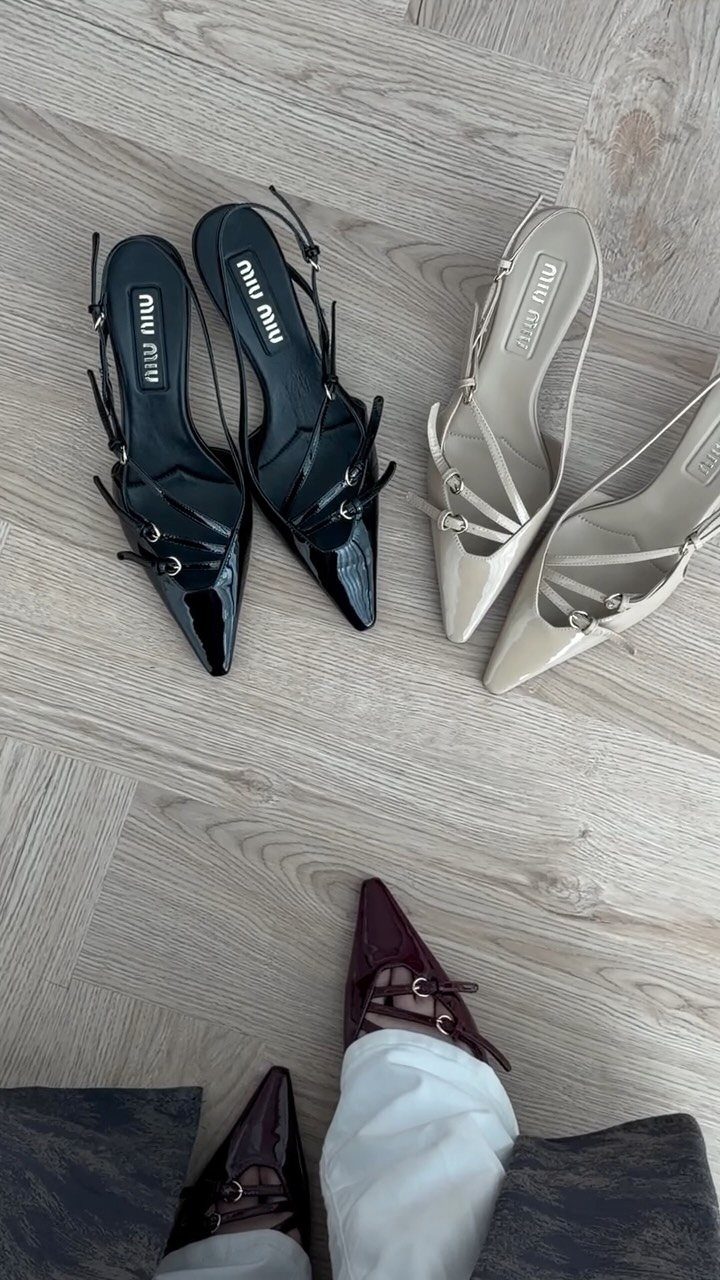 Burgundy pointed-toe sandals with straps worn with white trousers on wooden flooring