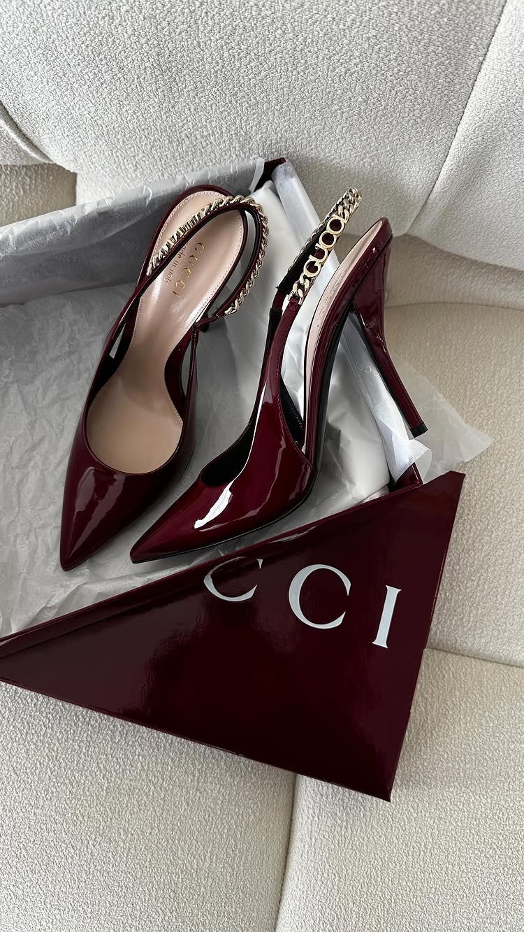Burgundy pointed-toe high heels with gold chain straps on white tissue paper.