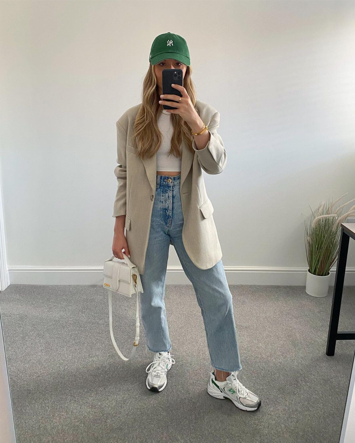 Woman wearing a beige blazer, light blue jeans, and white New Balance 530 sneakers.