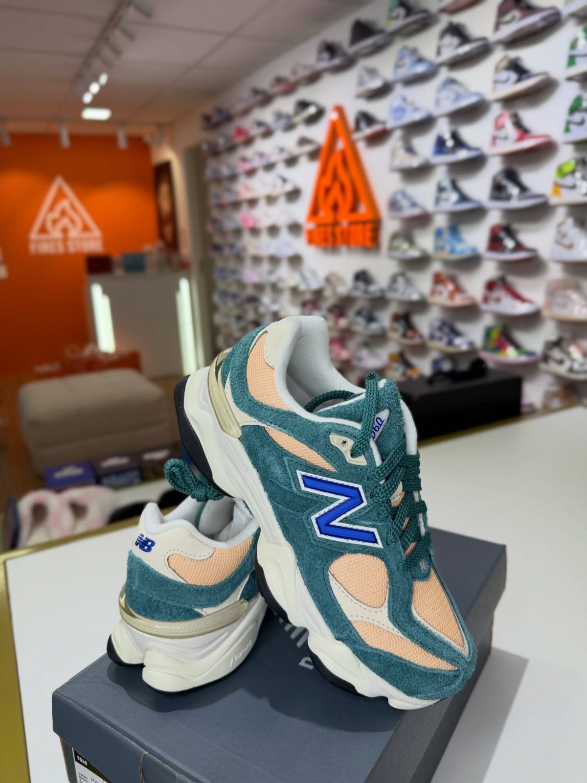 New Balance 9060 All Colors: 8 Pairs to Consider 5 Teal and peach New Balance 9060 sneakers sitting on a black shoebox.