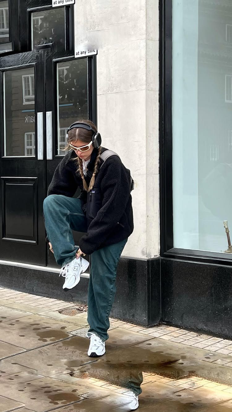 Person wearing dark teal wide-leg trousers and white chunky sneakers on a sidewalk