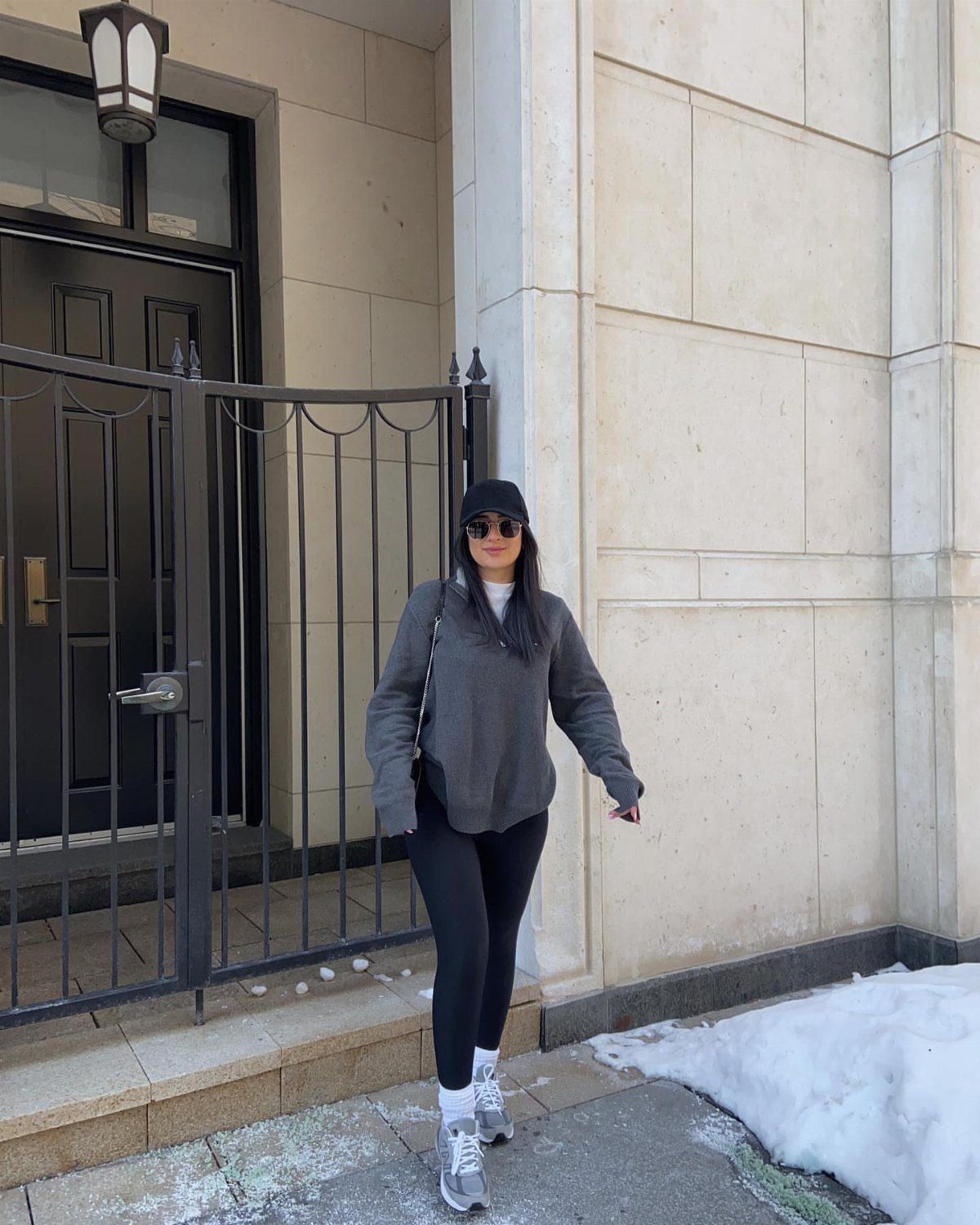 Woman wearing grey New Balance sneakers, black leggings, and a grey sweatshirt outdoors.