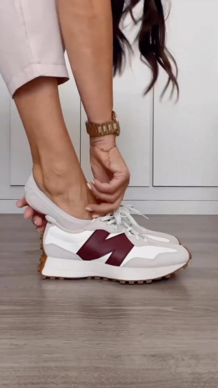 White and grey New Balance 327 sneakers with burgundy logo on a person