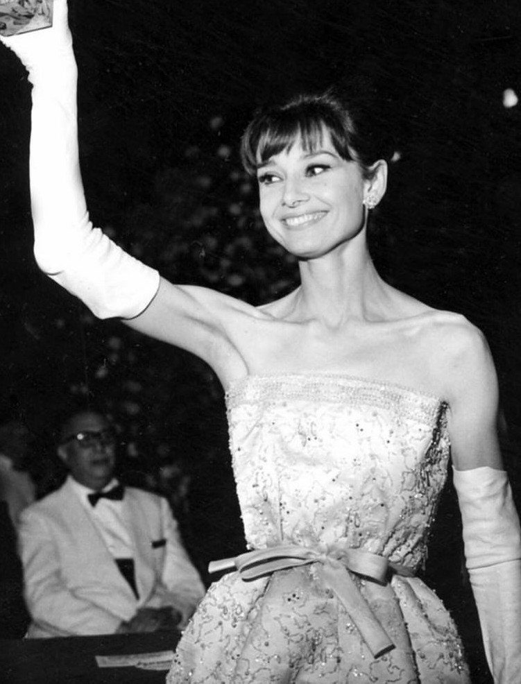 Woman in a strapless embellished evening gown and white opera gloves smiling.