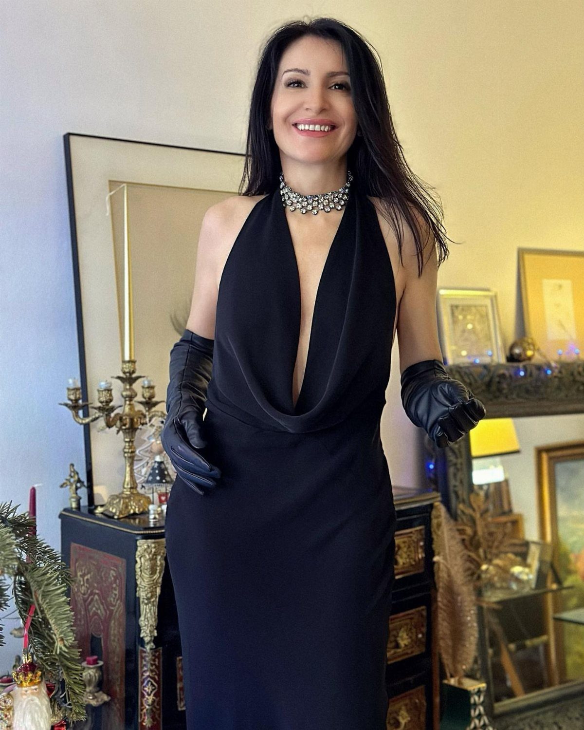 Woman in a black plunging gown with leather gloves and a silver choker.