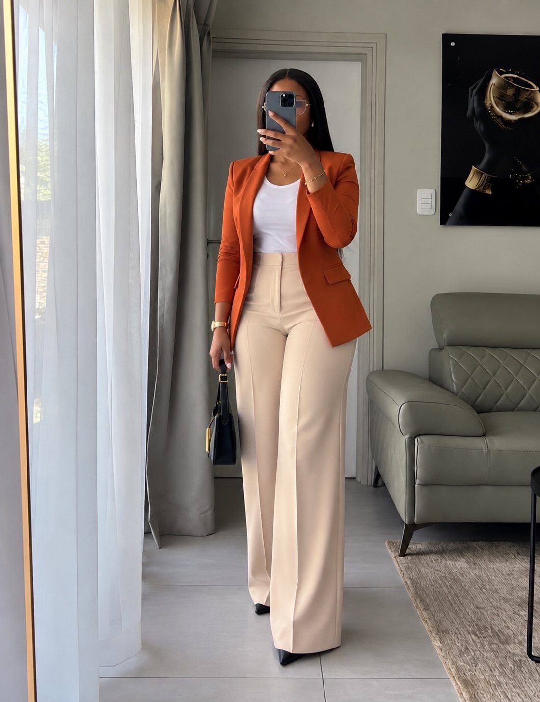 Woman wearing an orange blazer and beige wide-leg trousers for a professional look.