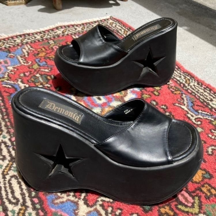 Black faux-leather platform sandals with star cutouts on a patterned red rug