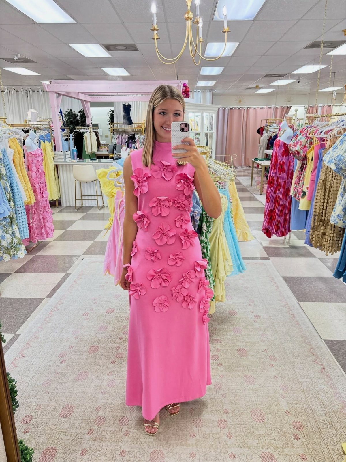 Woman in a bright pink long dress with 3D floral details in a boutique