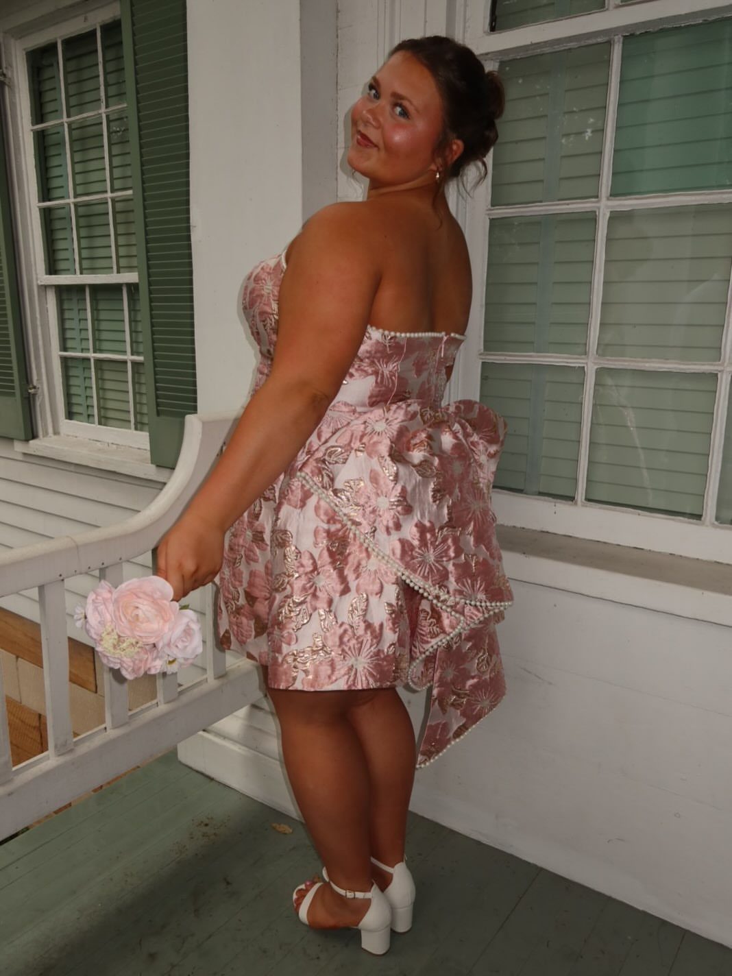 Woman in a short pink floral strapless dress with a large back bow.