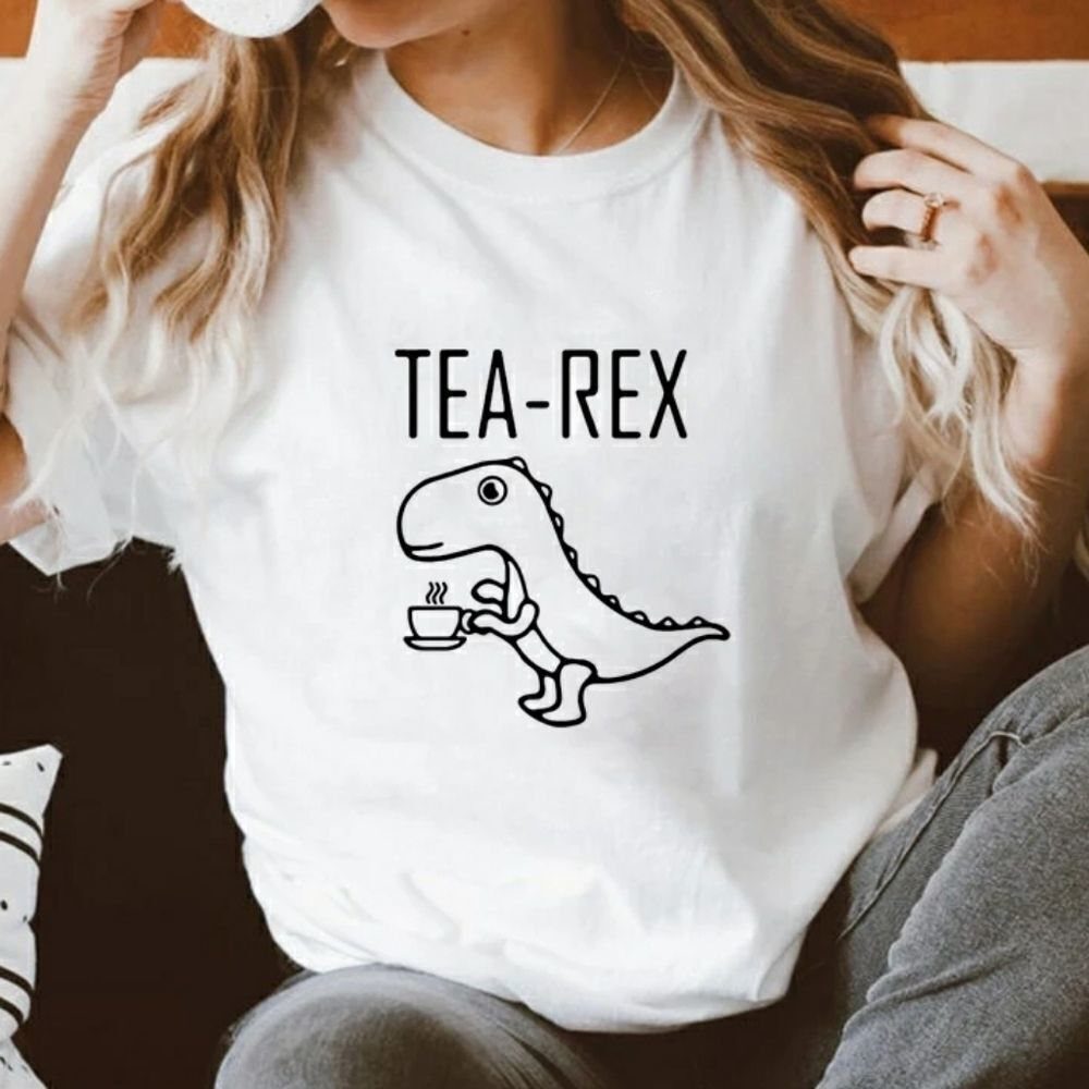 White t-shirt with a funny Tea-Rex dinosaur graphic worn by a person.