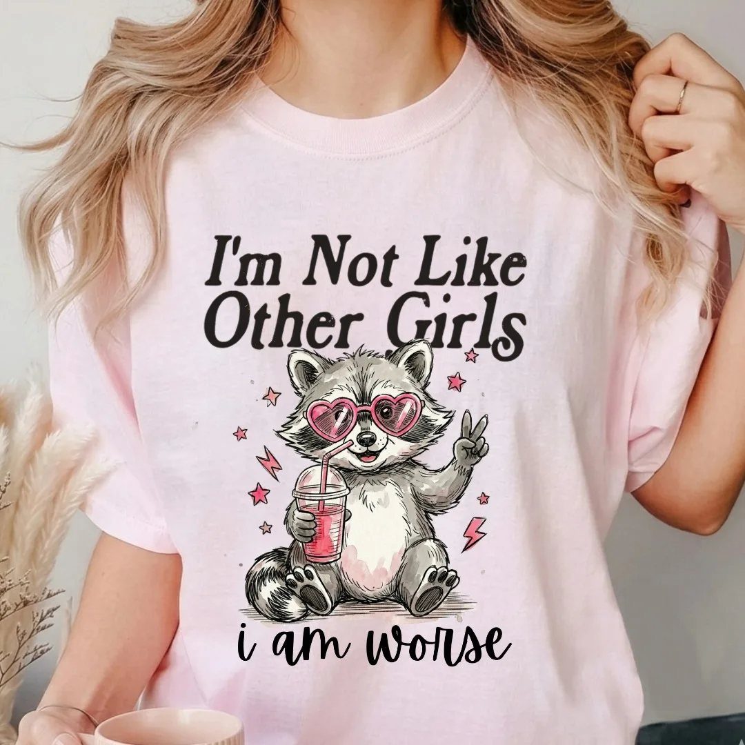Person wearing a pink t-shirt with a raccoon graphic and humorous text.