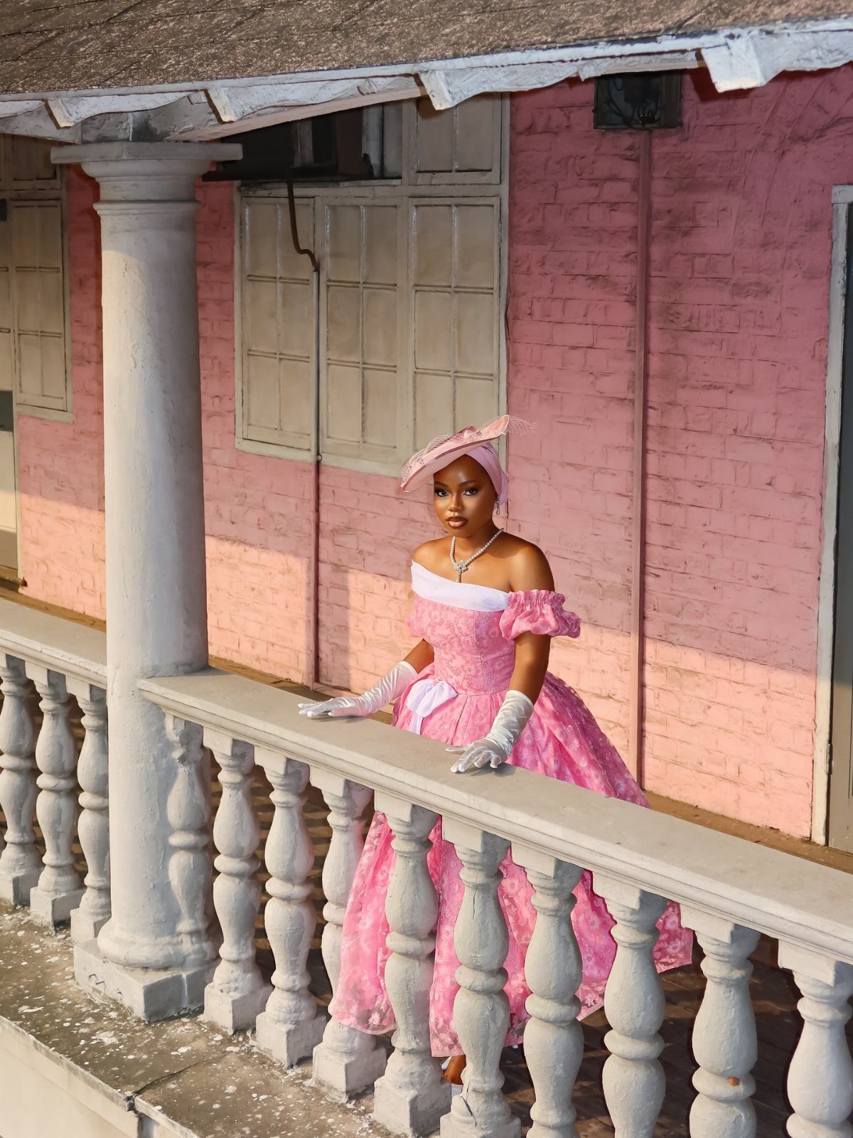 Woman in a pink regency era ball gown posing on a white balcony