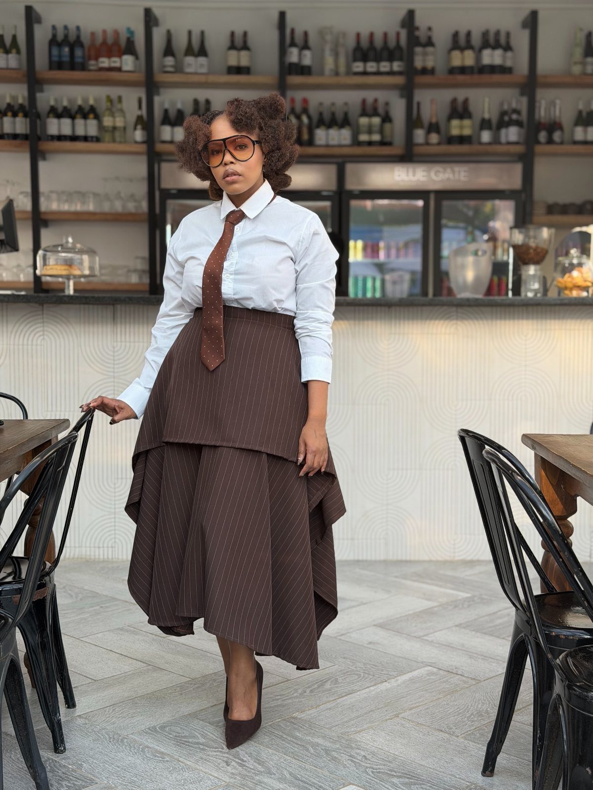 Woman in white shirt, brown tie, and layered brown skirt in a restaurant
