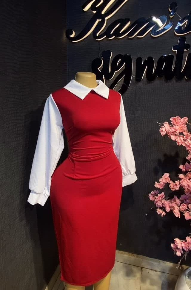 Red sheath dress with white collared shirt on a mannequin against dark wall
