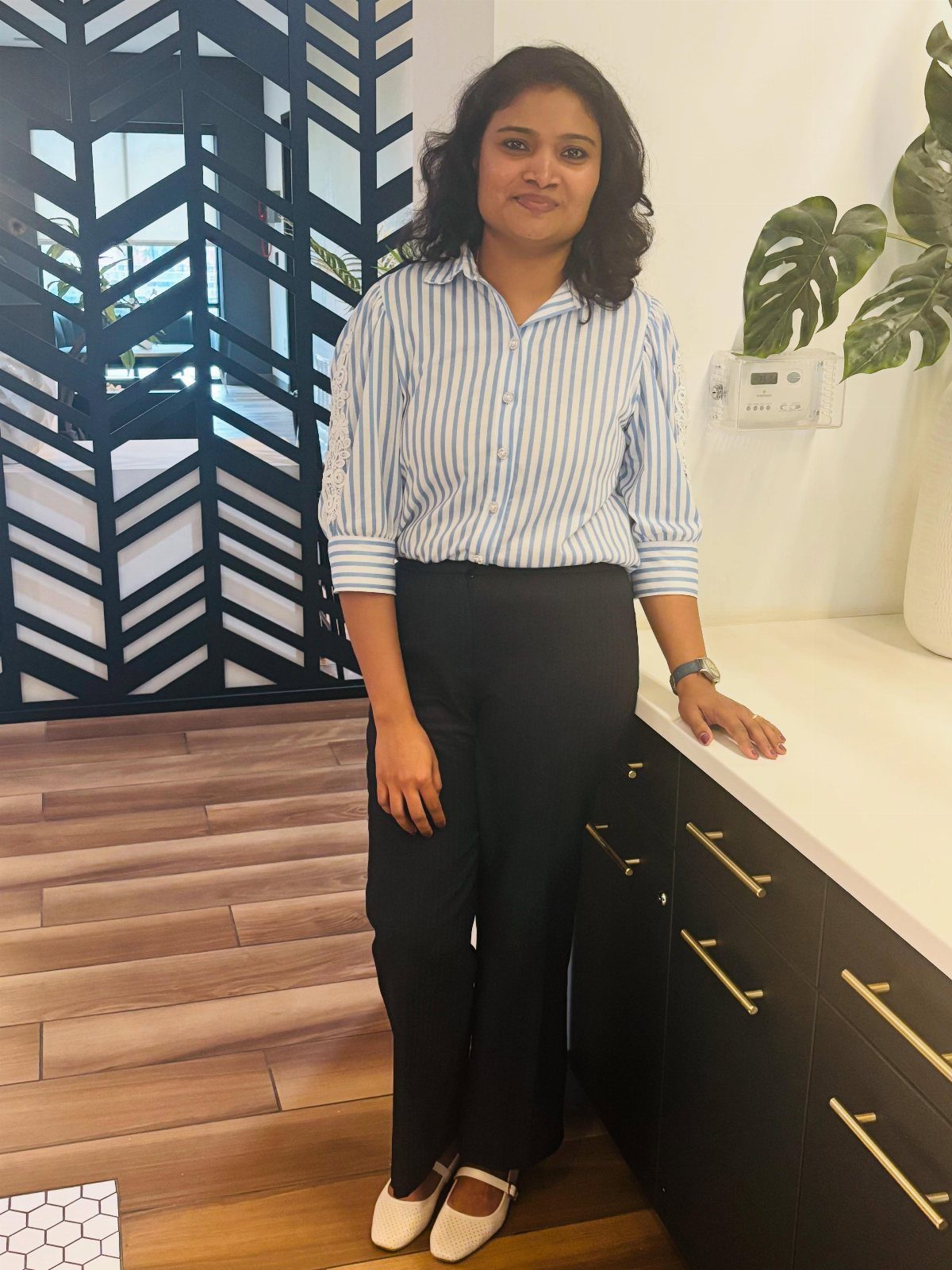 Woman wearing a striped shirt and black trousers standing in a modern kitchen