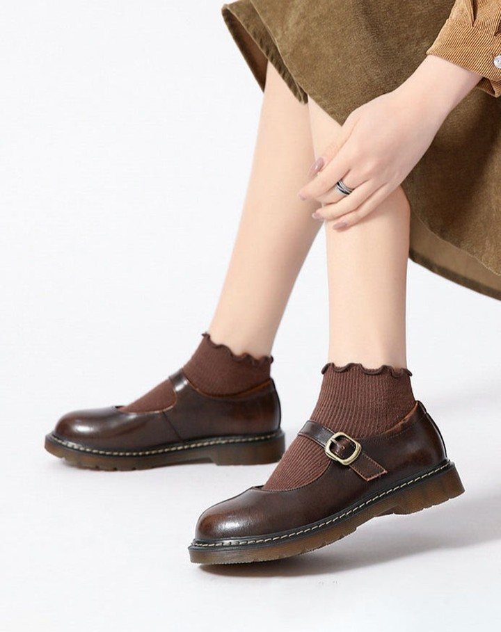 Brown leather Mary Jane shoes with gold buckles and brown ribbed socks.