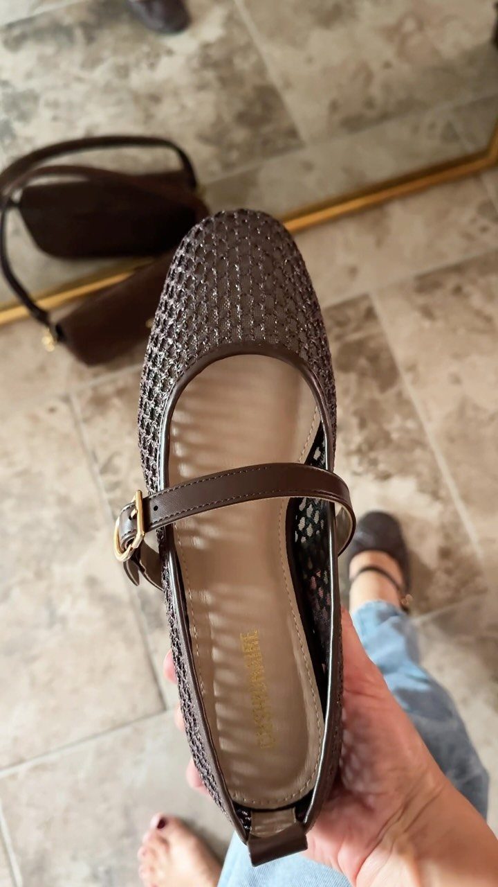 Brown woven Mary Jane flat shoe with a strap held over tiled floor