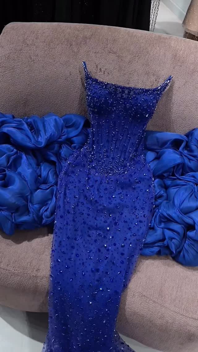 Royal blue floor-length gown with beaded bodice resting on a beige chair.