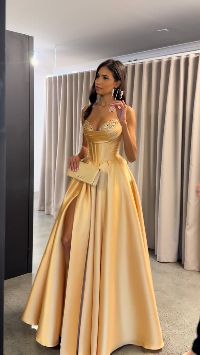 Woman in a gold satin ball gown with a corset bodice and high slit.