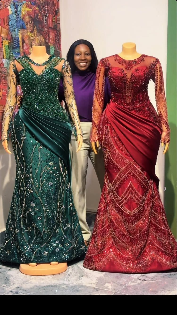 Emerald green and burgundy red beaded gowns on mannequins with a woman standing between.