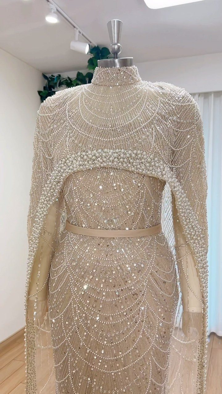 Champagne beaded gown with a matching capelet displayed on a dress mannequin.
