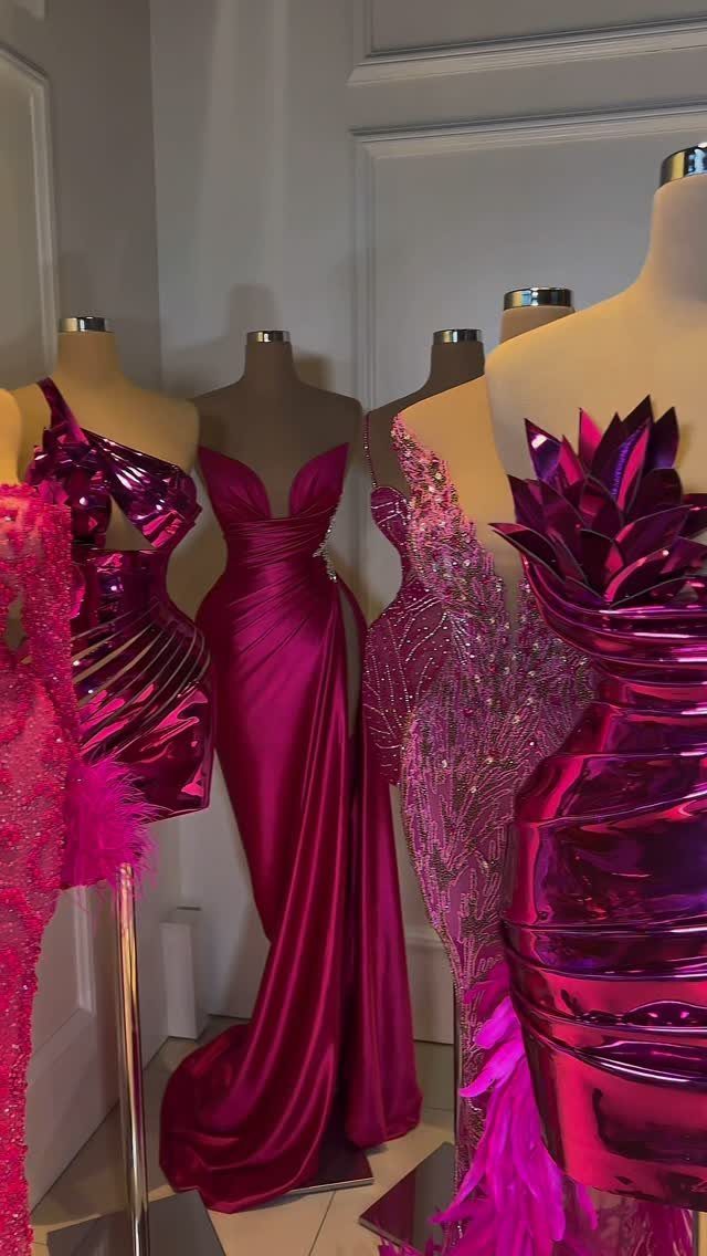 Magenta and pink formal gowns displayed on mannequins in a white room.