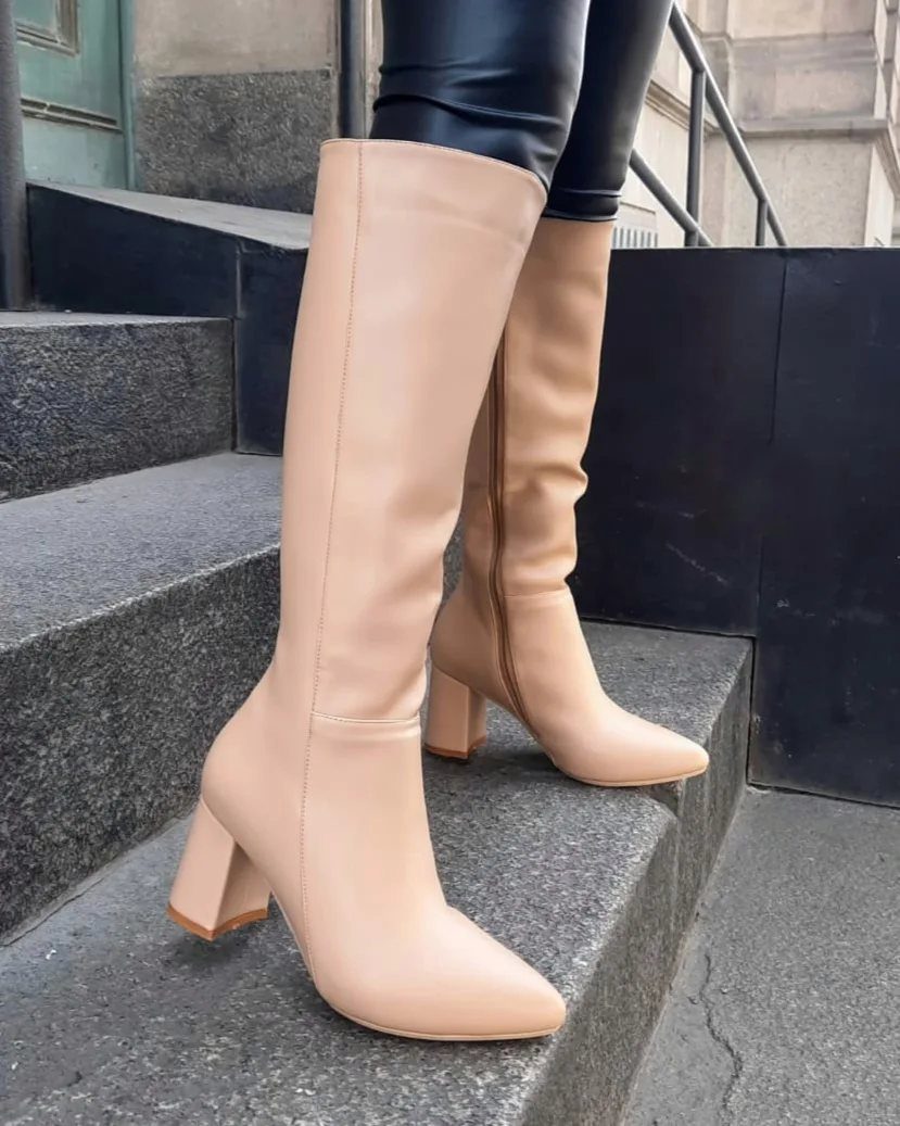 Beige leather knee-high boots with block heels worn with black leather leggings.