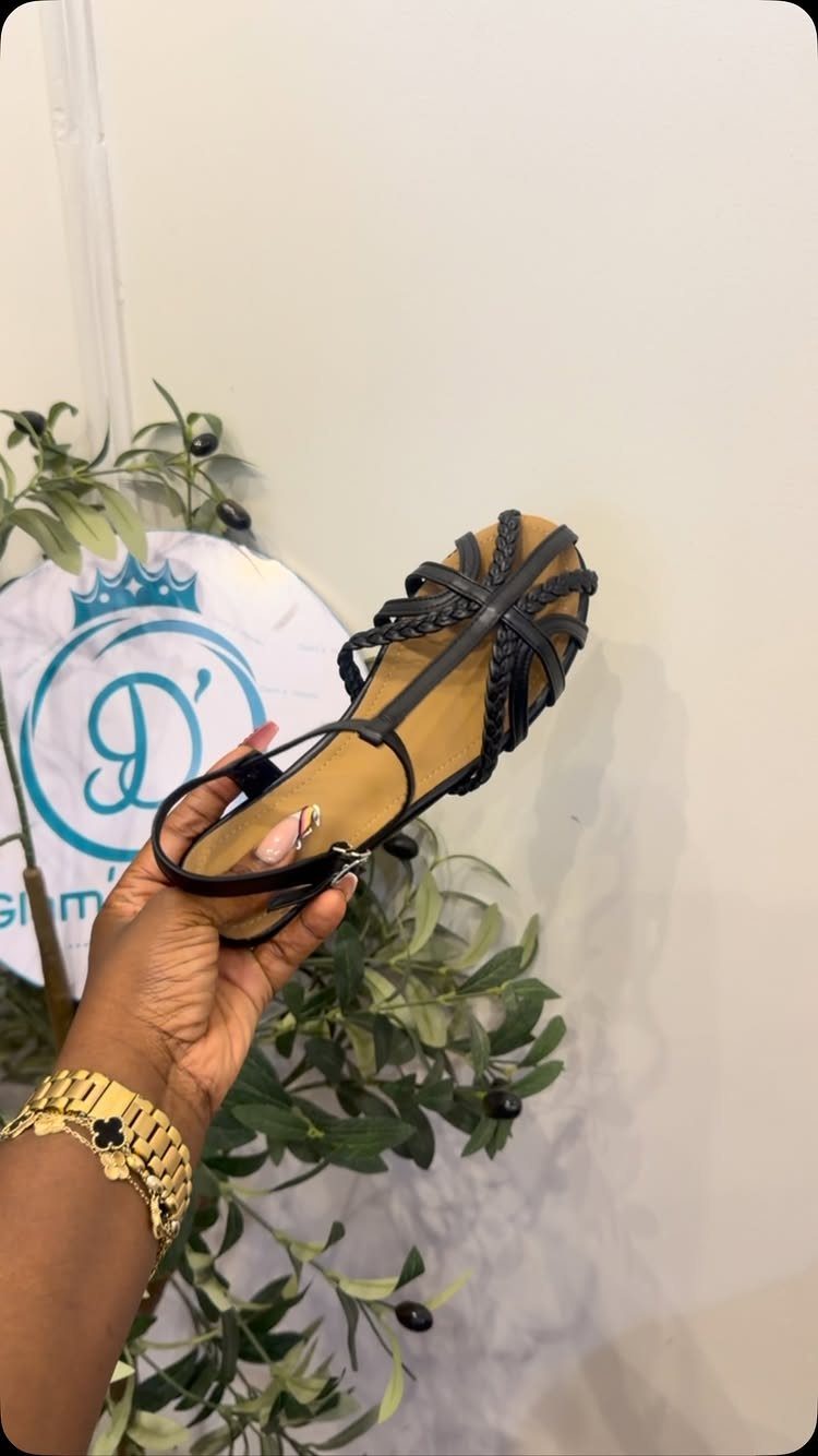 5 Strappy Flip Flops for Women, from Flat to Platform 3 Black flat strappy sandal held by a hand against a white wall background