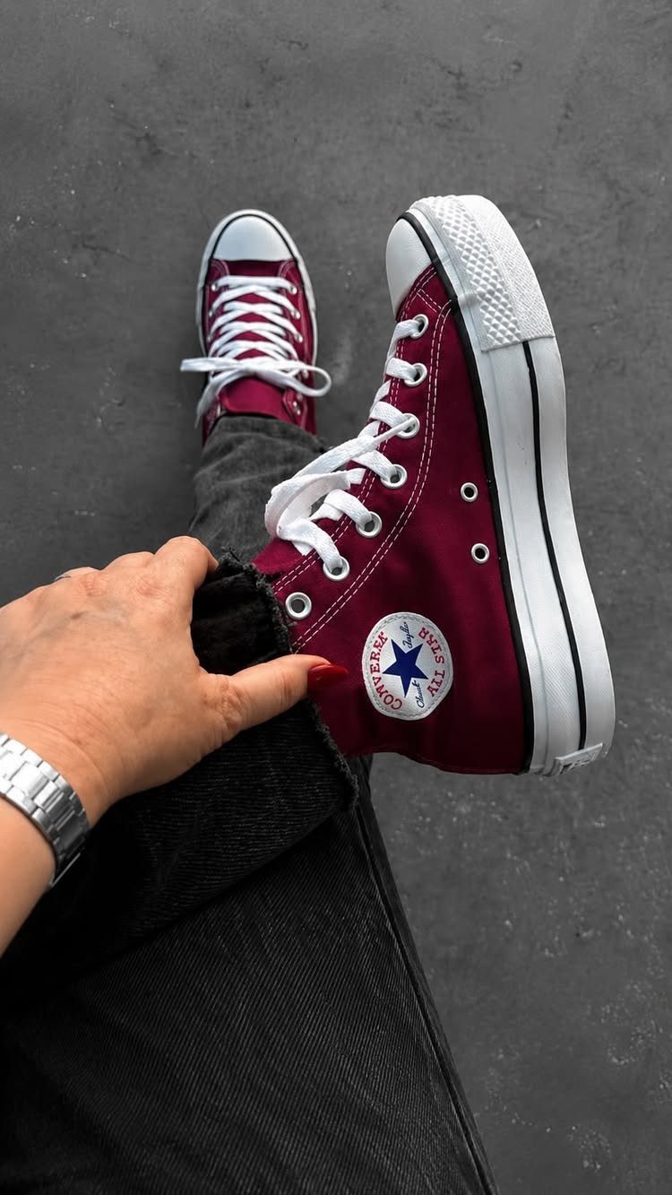 Maroon high-top Converse sneakers with white laces worn with dark grey jeans.