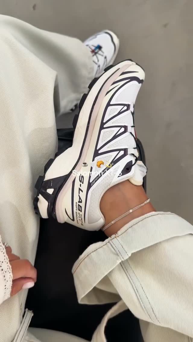 Rugged white and black gorpcore sneakers worn with off-white wide-leg trousers.